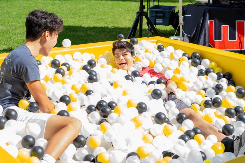 Two students laugh in a ball pit set-up for Fresh Check on the quad.