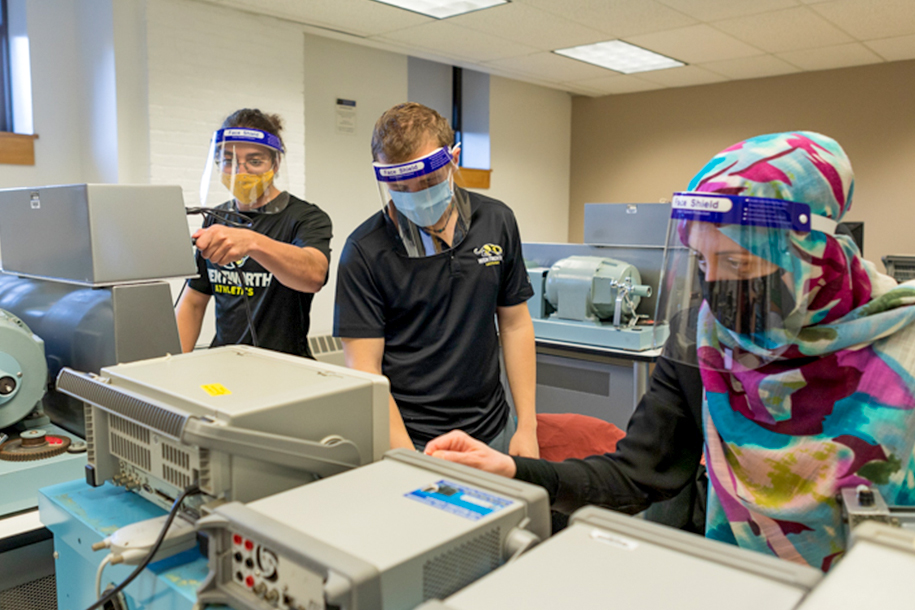 3 people work in a lab standing over machines