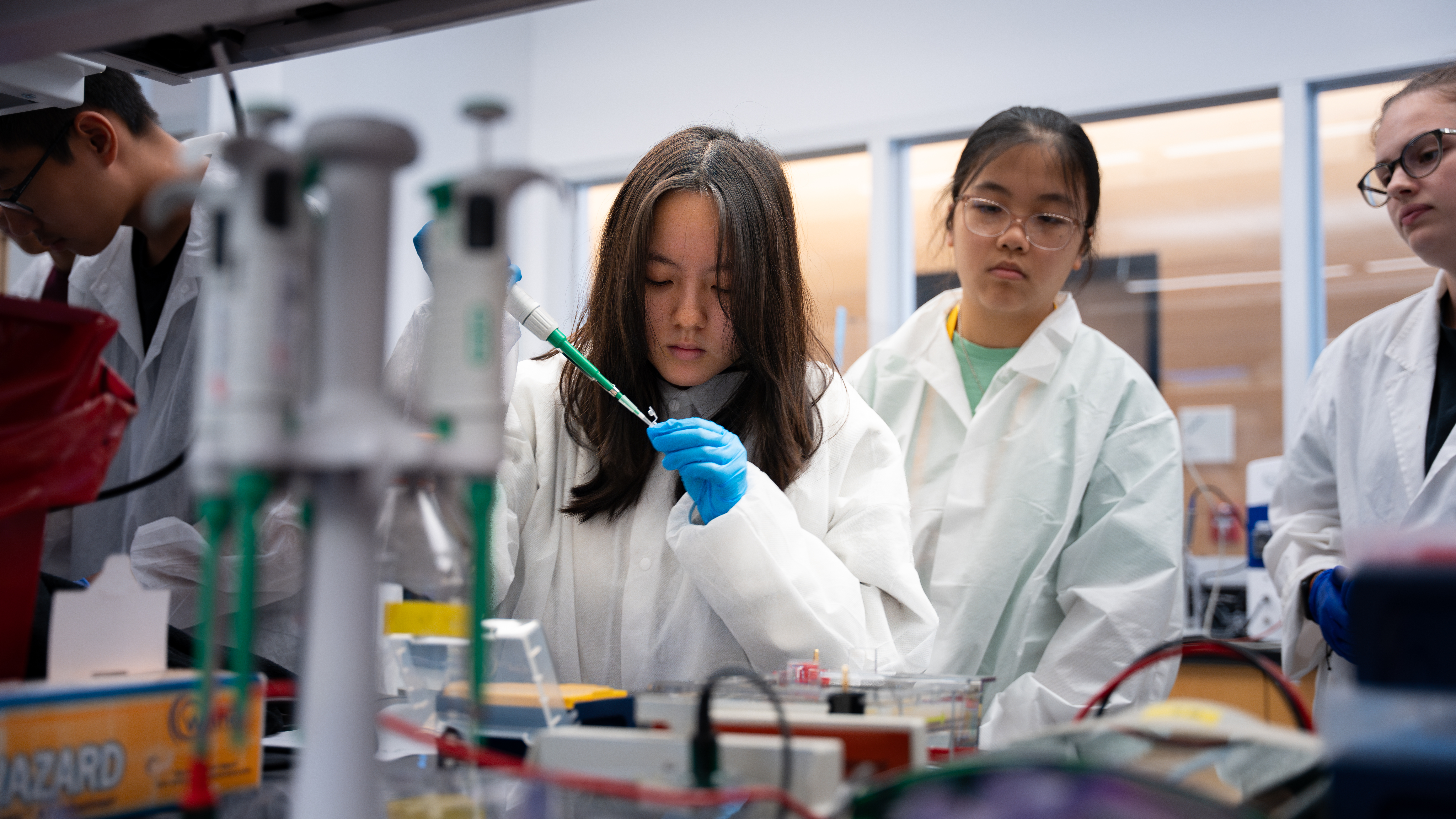 Two students working within the lab using pipettes.