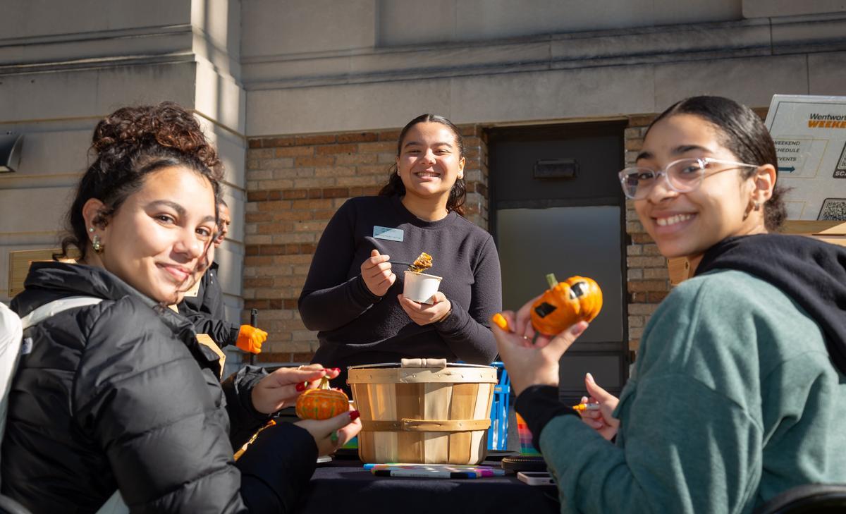 Three female students paint pumpkins at Campus Fest