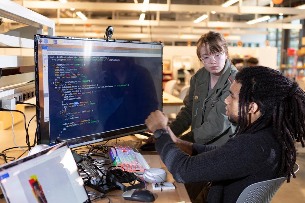 two students discussing code on screen