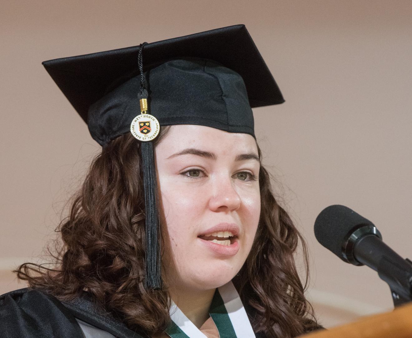 woman speaking while wearing graduation cap