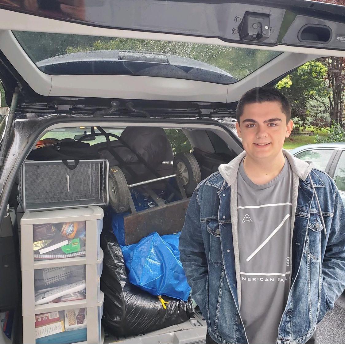 student standing beside car