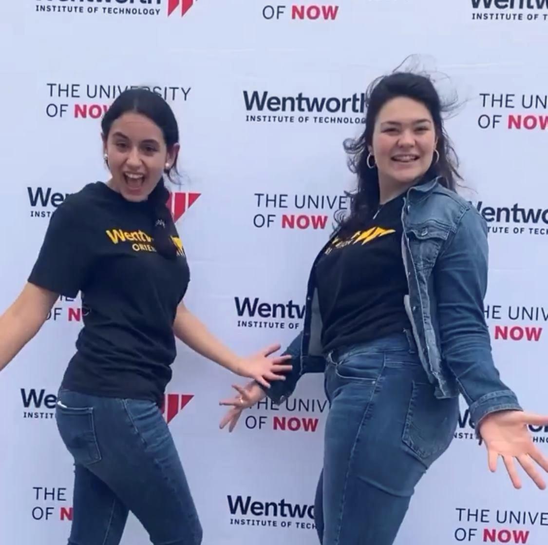 two women stand in front of sign