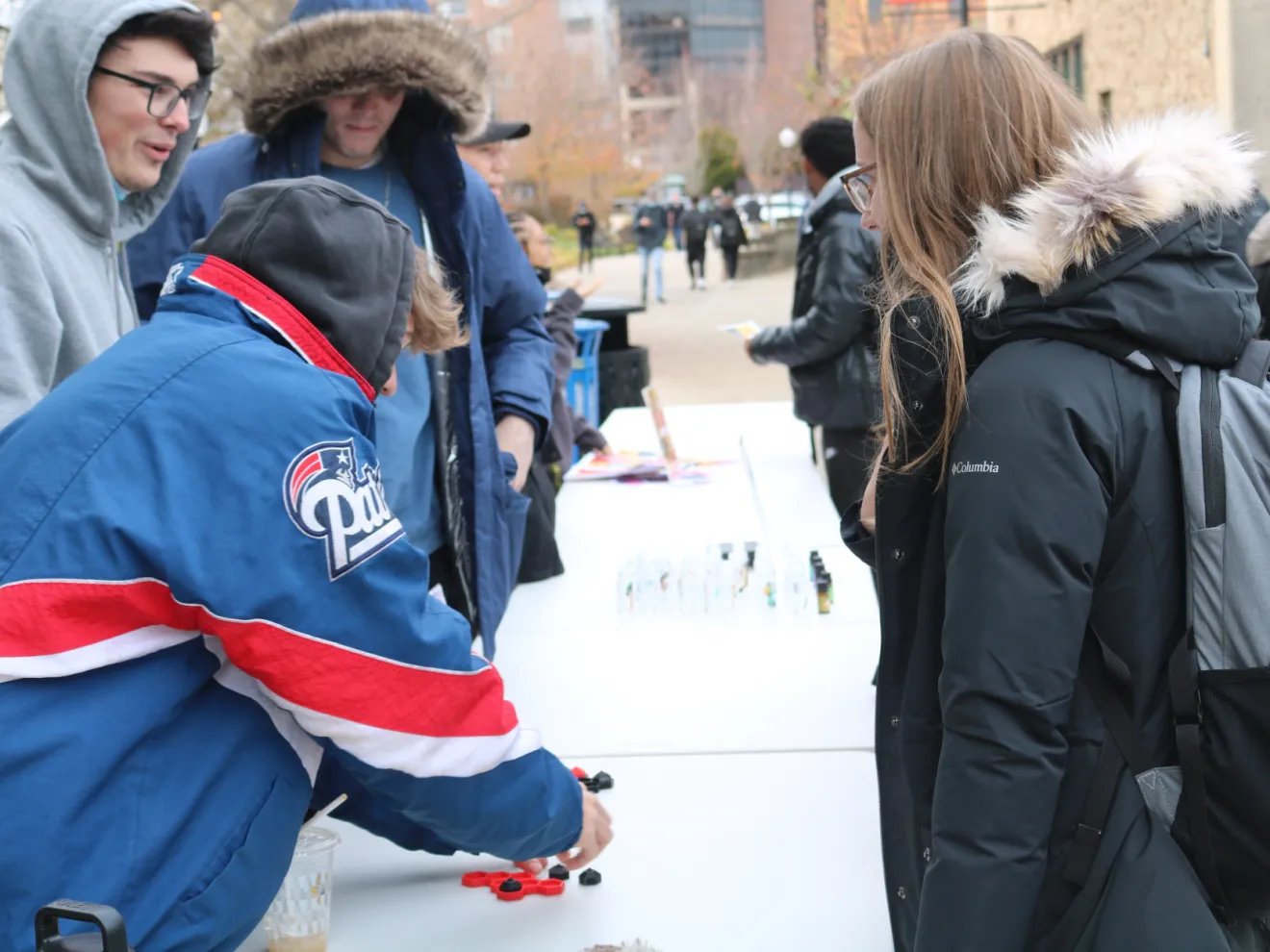 people selling and buying items outside at a table