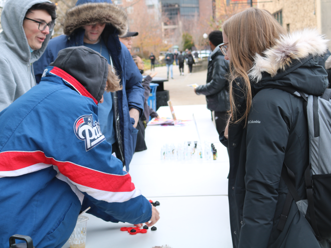 people selling and buying items outside at a table