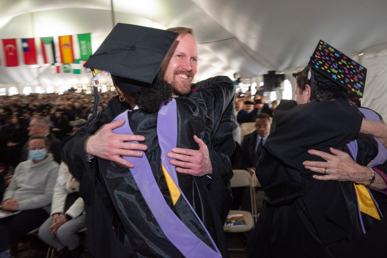 people in graduation robes hugging
