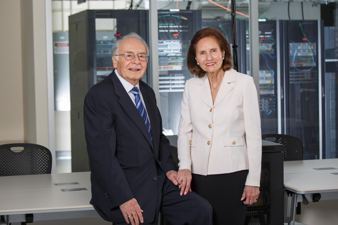 portrait of two people sitting in front of a computer server room