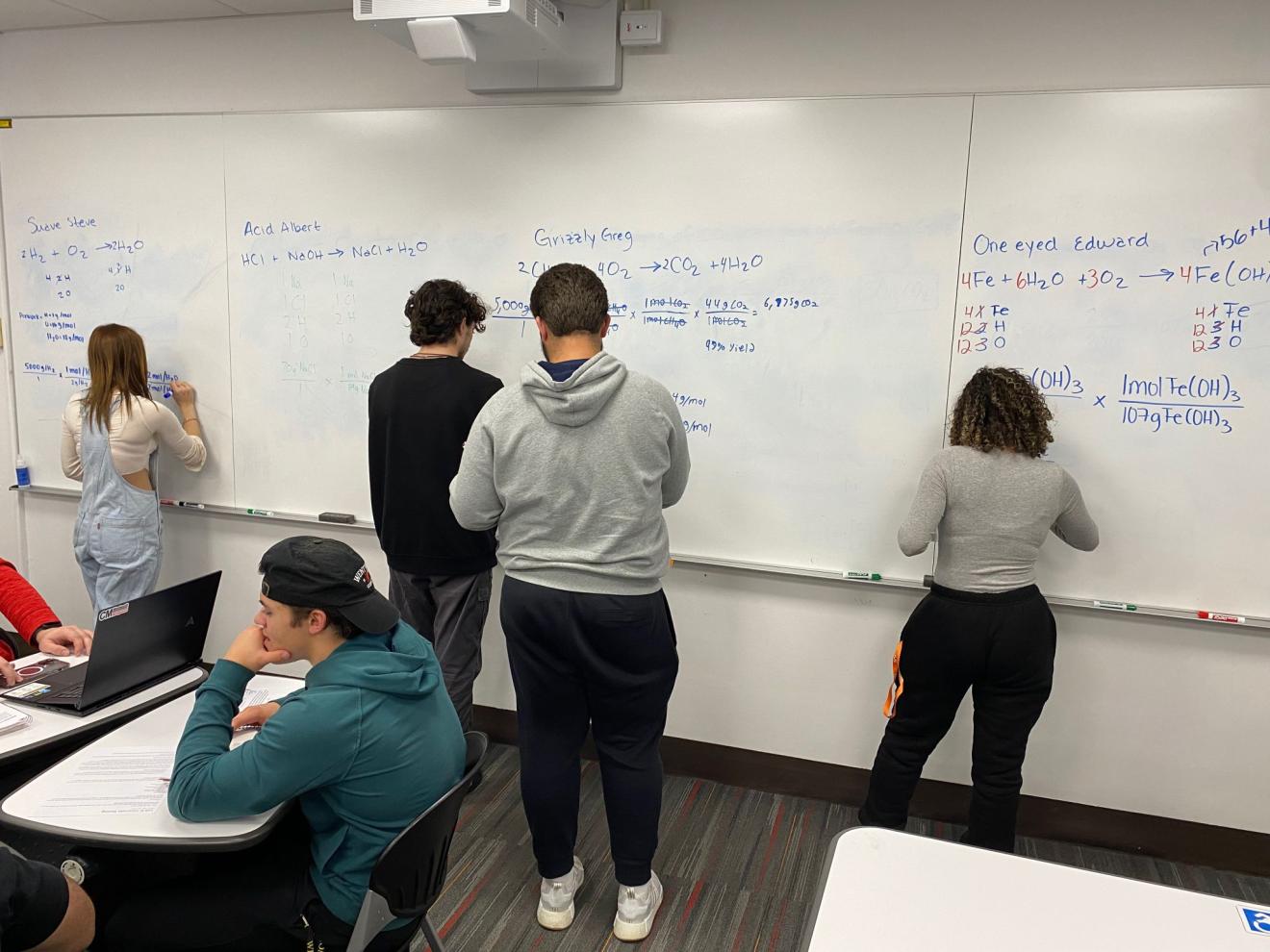 students working on a whiteboard in a classroom
