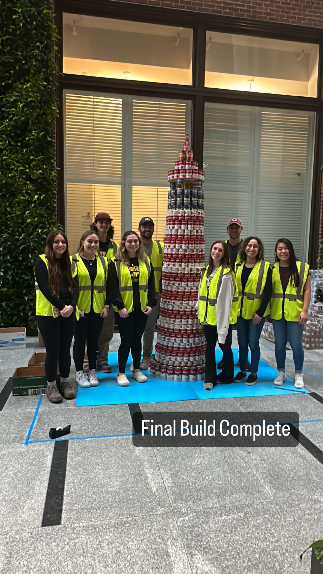 people standing next to a tower of cans