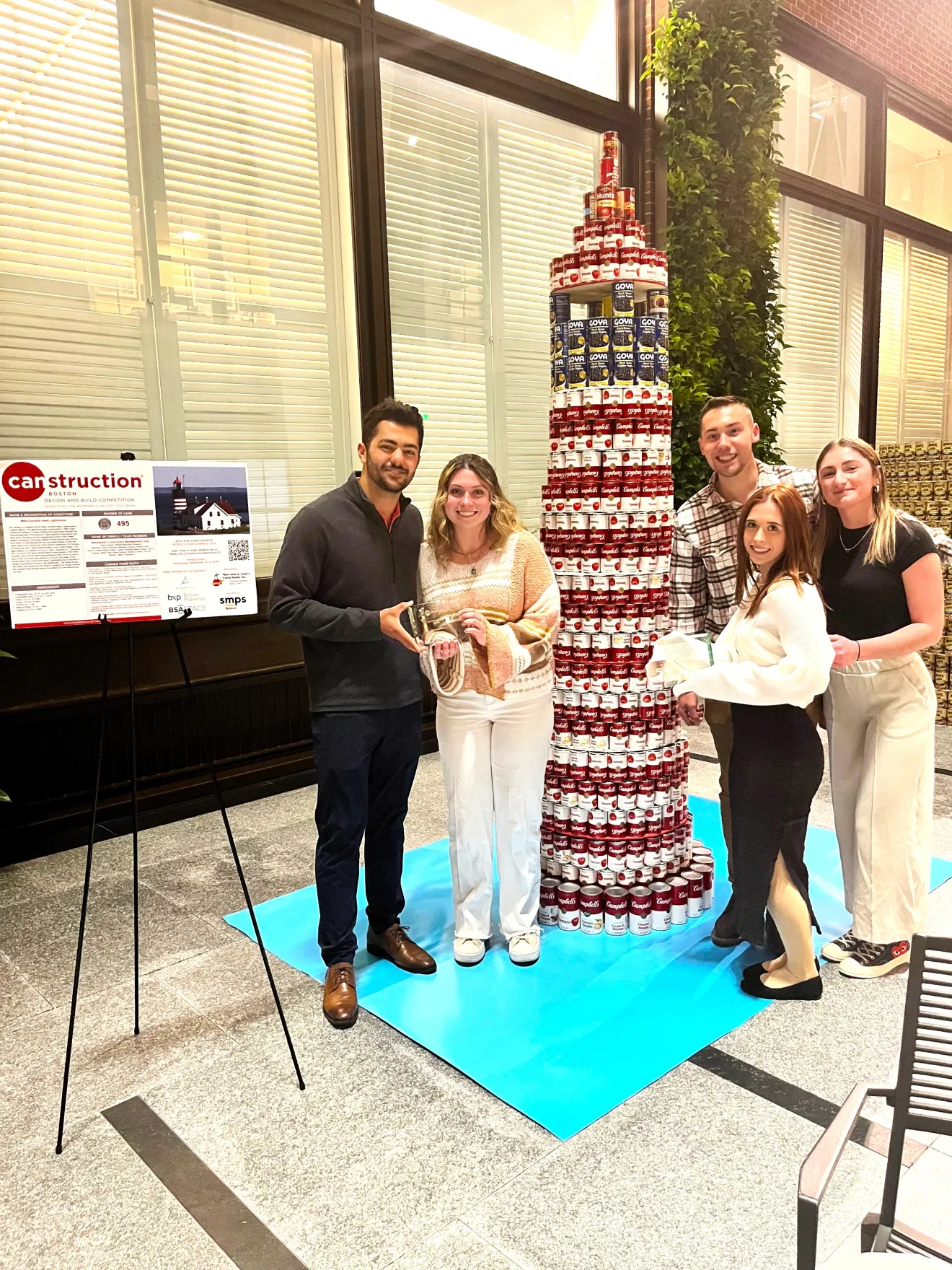 people standing next to a tower of cans