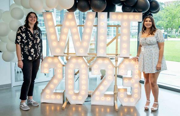 women standing in front of a large 2023 sign