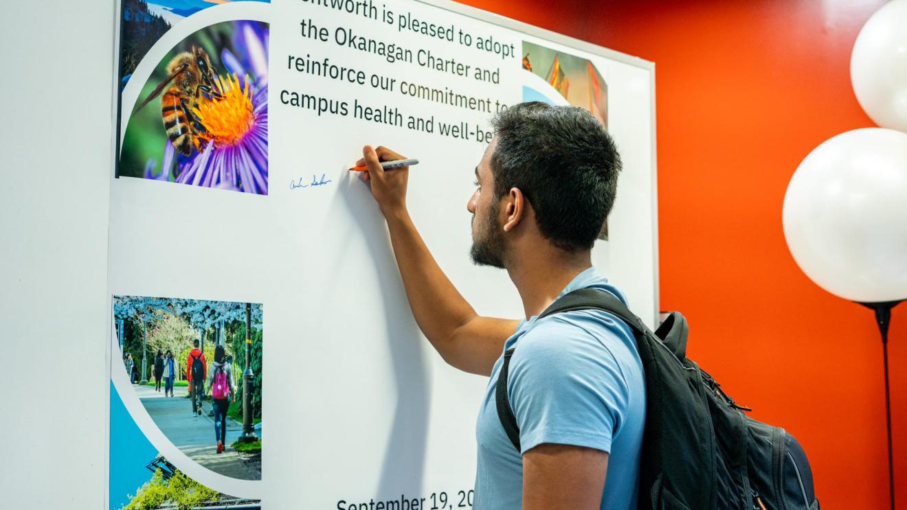 man signs a wall with a marker