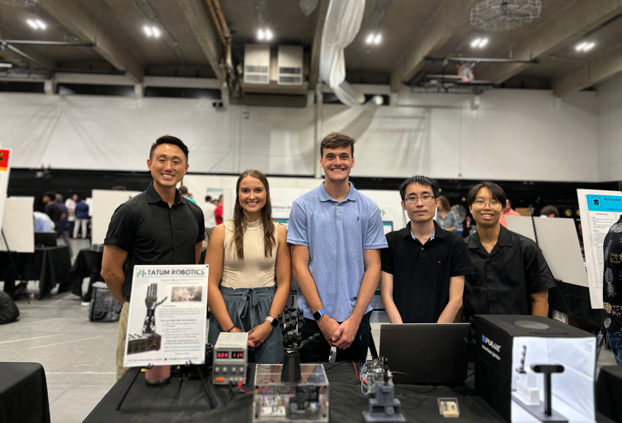 team of students behind a table containing a robotic hand