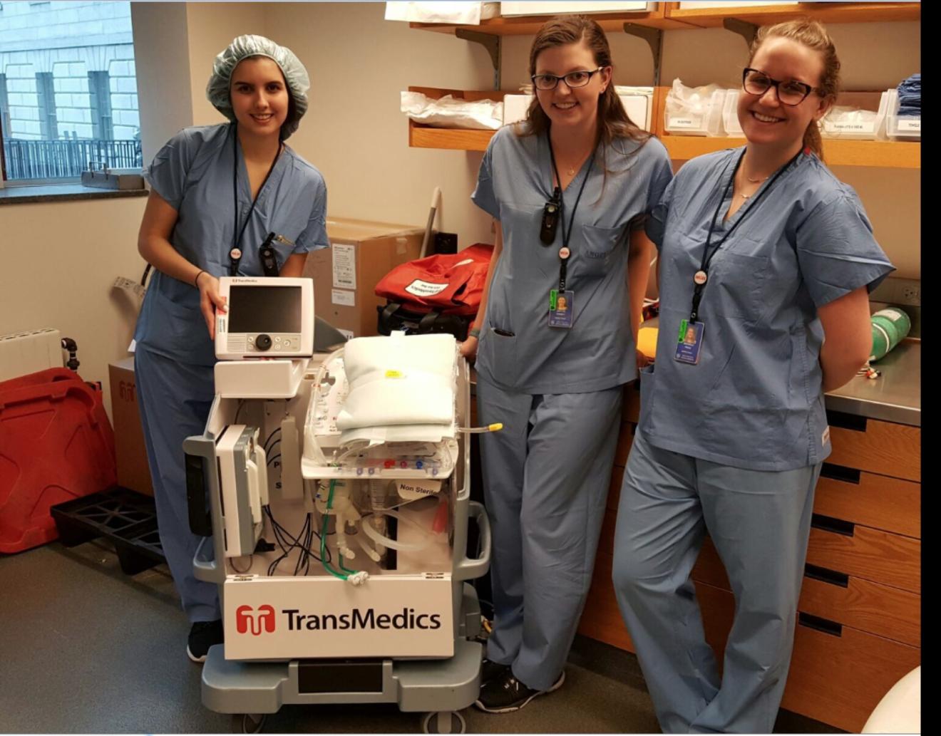 people in hospital scrubs standing by a machine