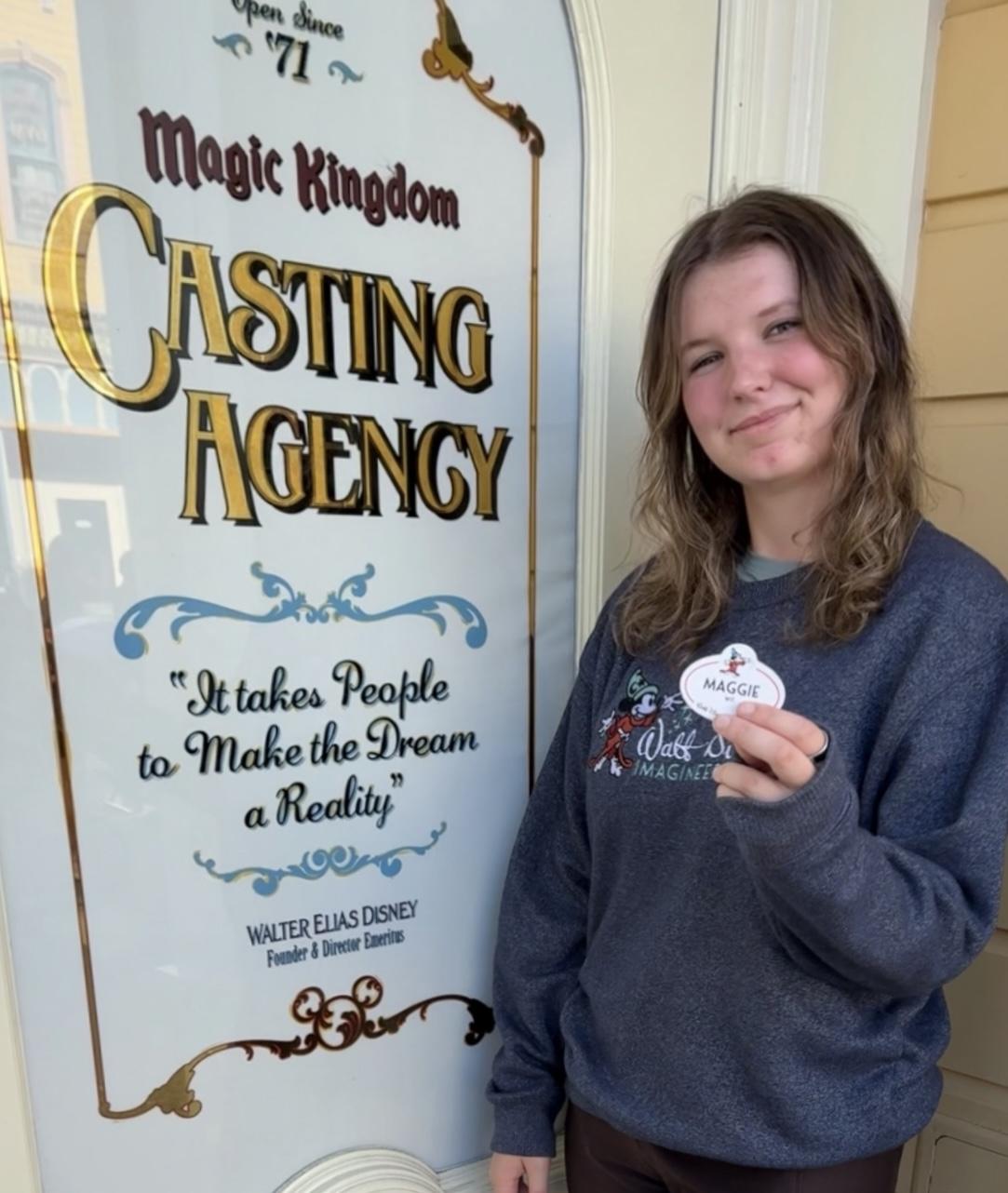 a woman stands in front of a sign reading "cast members"