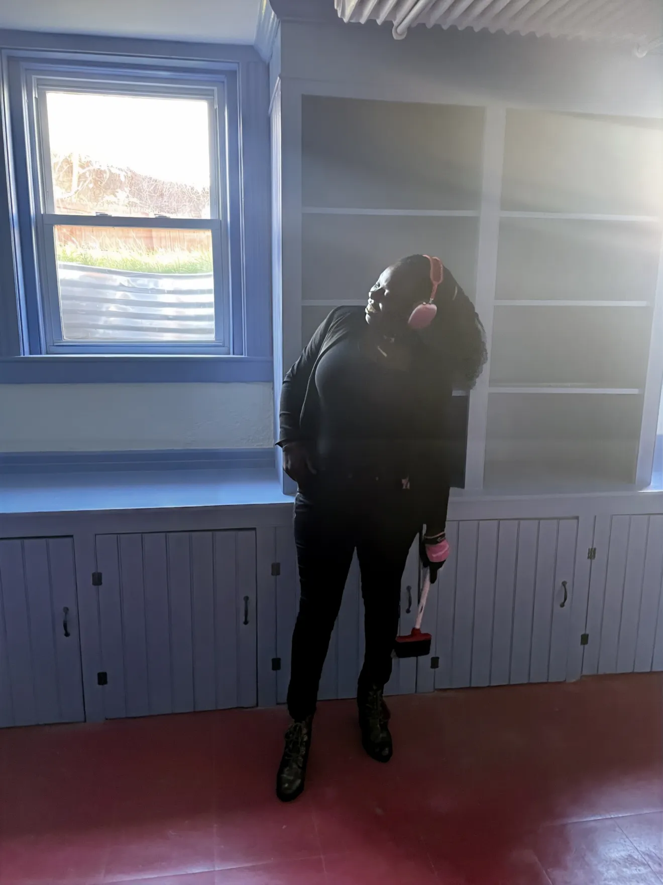a woman stands in front of a window in a kitchen