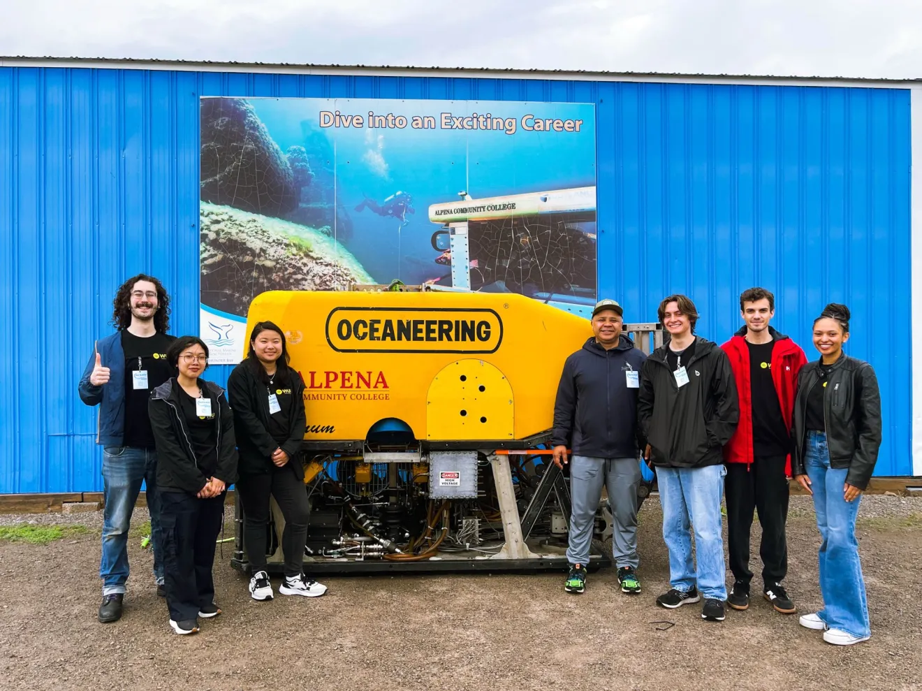 students stand in front of a poster advertising underwater robotics
