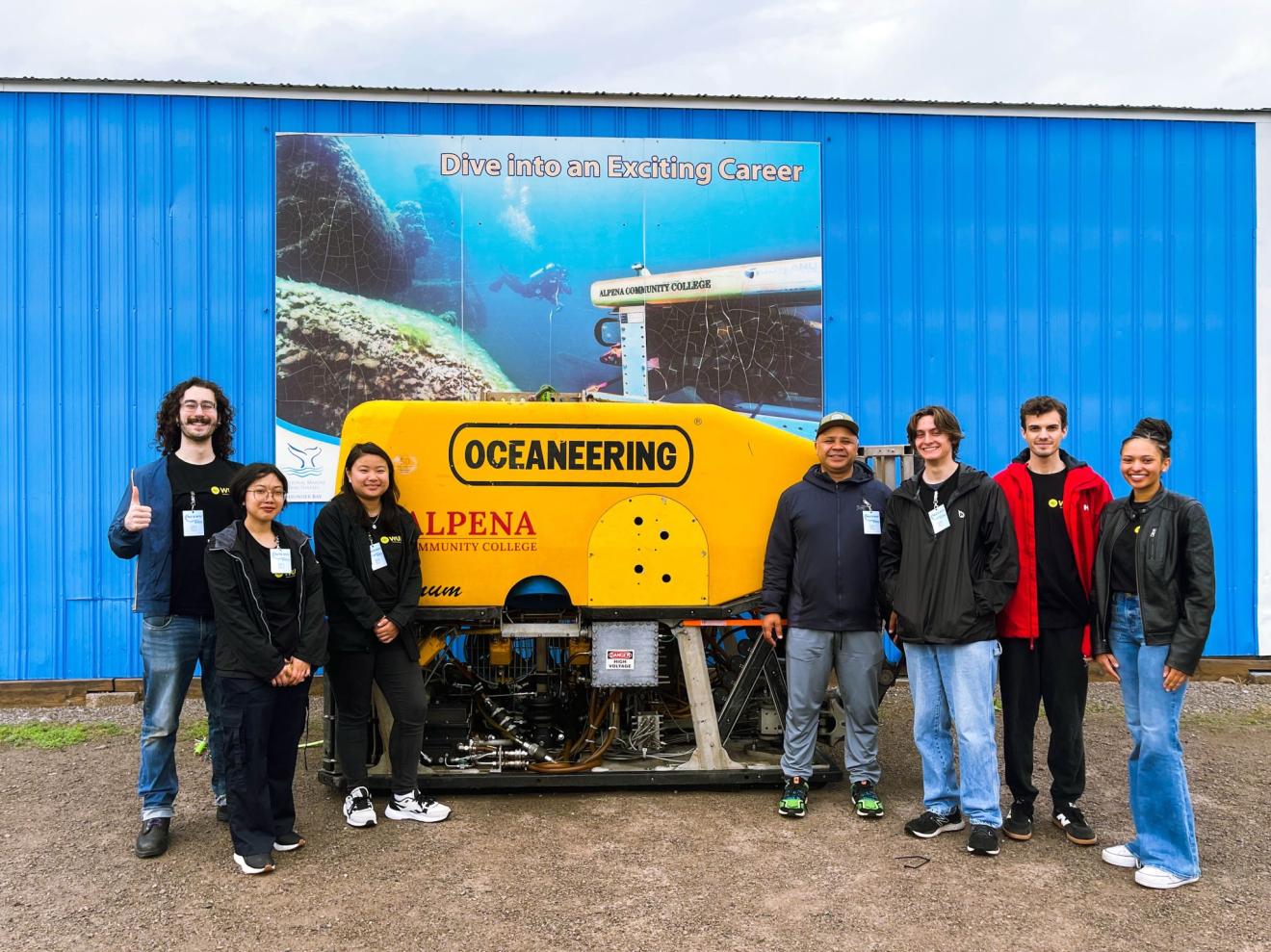 students stand in front of a poster advertising underwater robotics