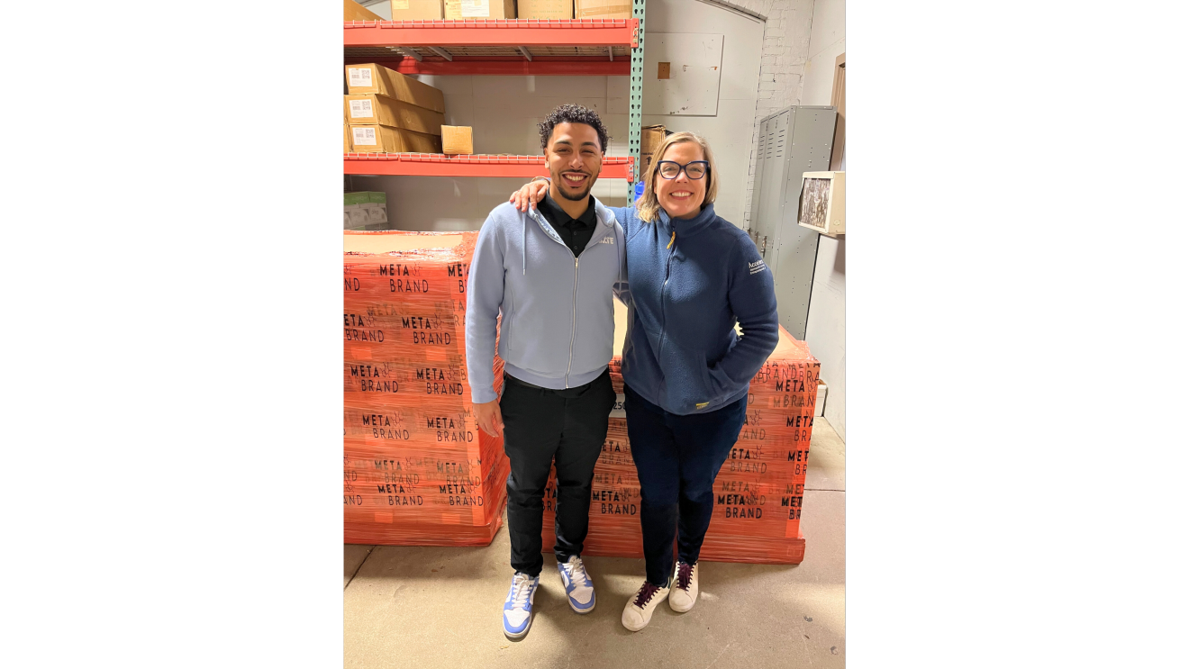 two people standing in front of pallets of beverages