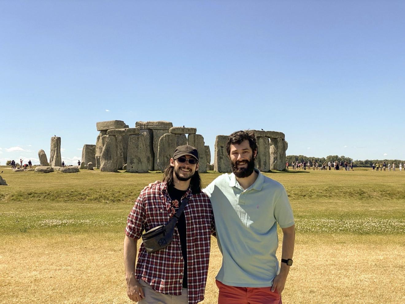 two men stand in front of england's stonehenge rock formation