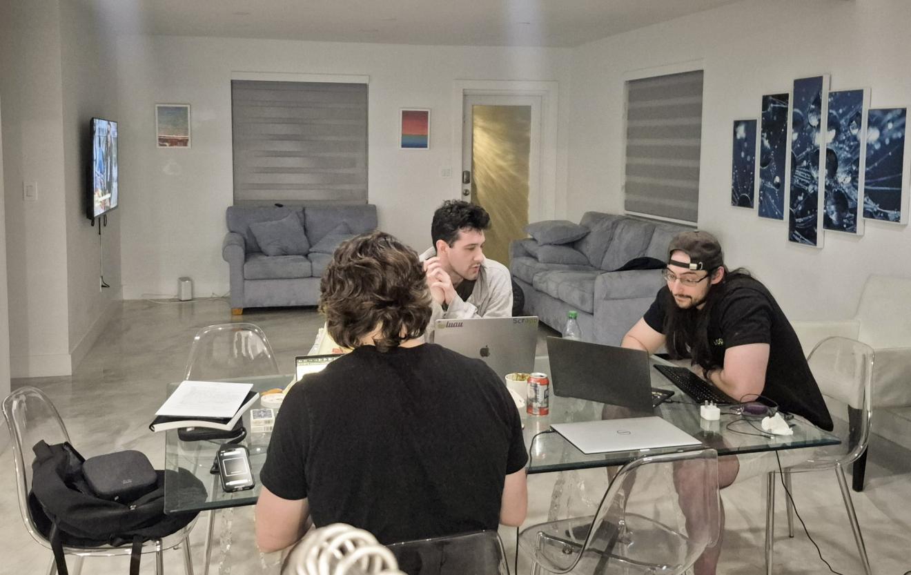 three men sit at a desk working
