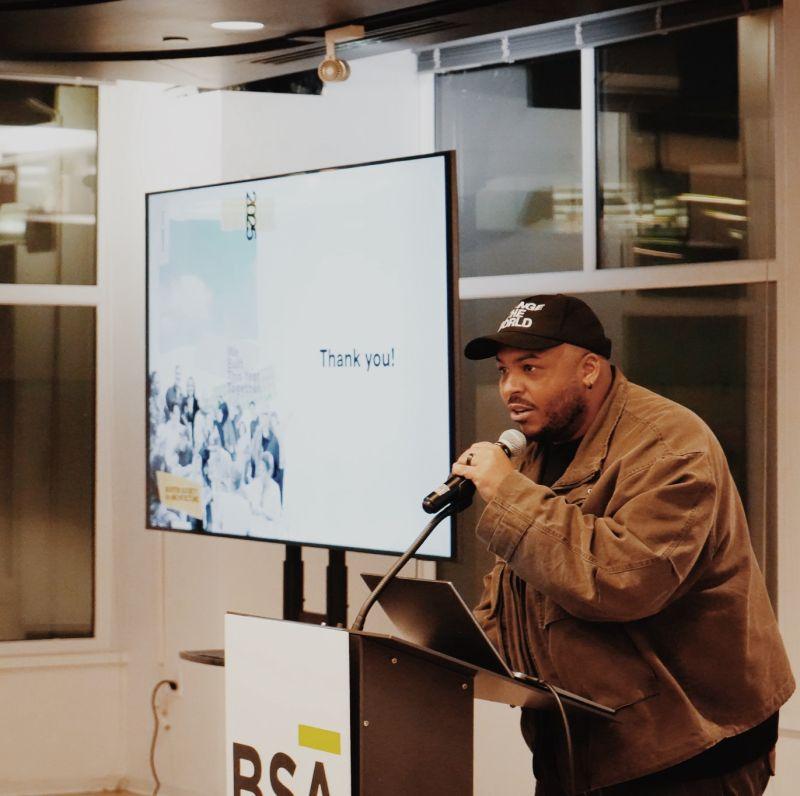 a man wearing a hat speaks at a podium