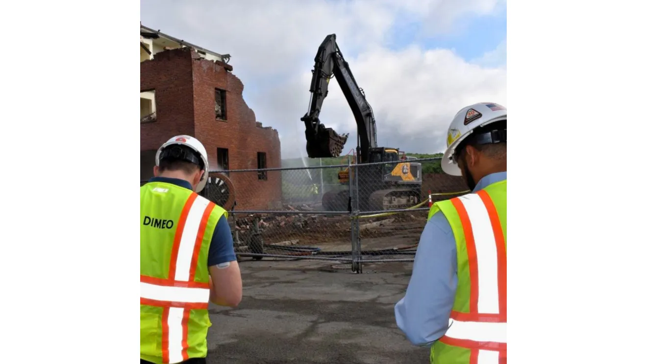 two people in hard hats and vests facing a construction site