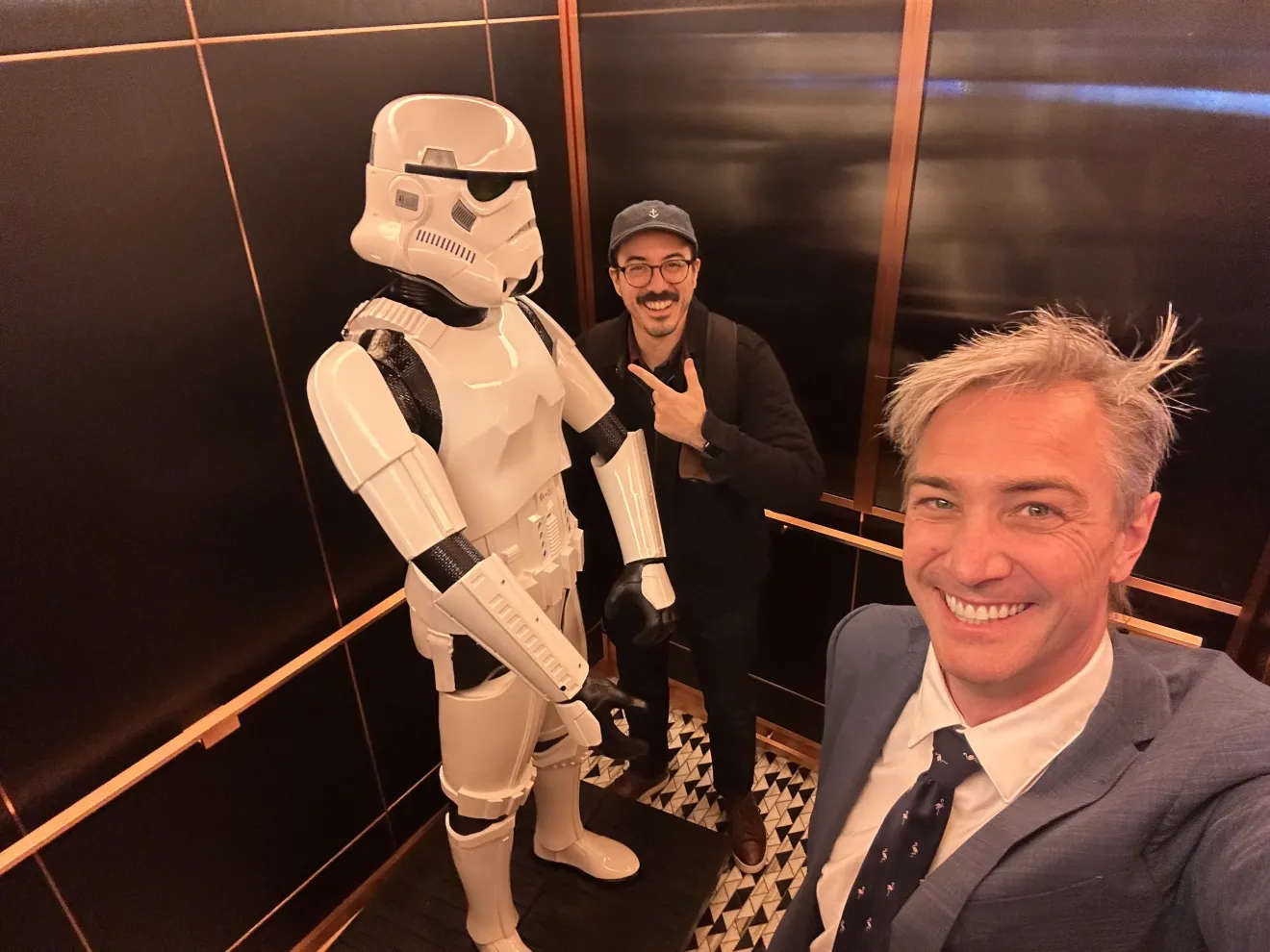 two men stand next to a star wars stormtrooper character