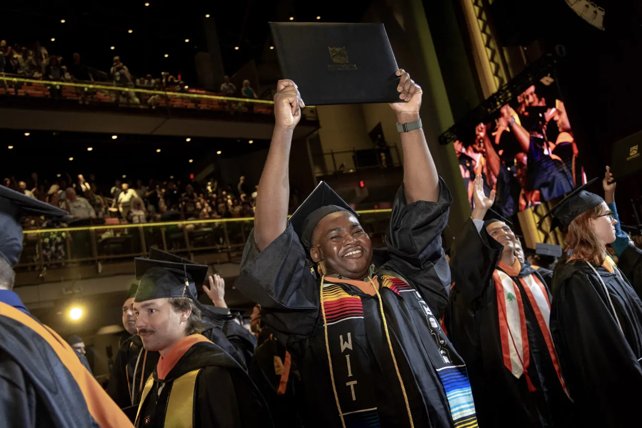 an excited graduate holds up his diploma