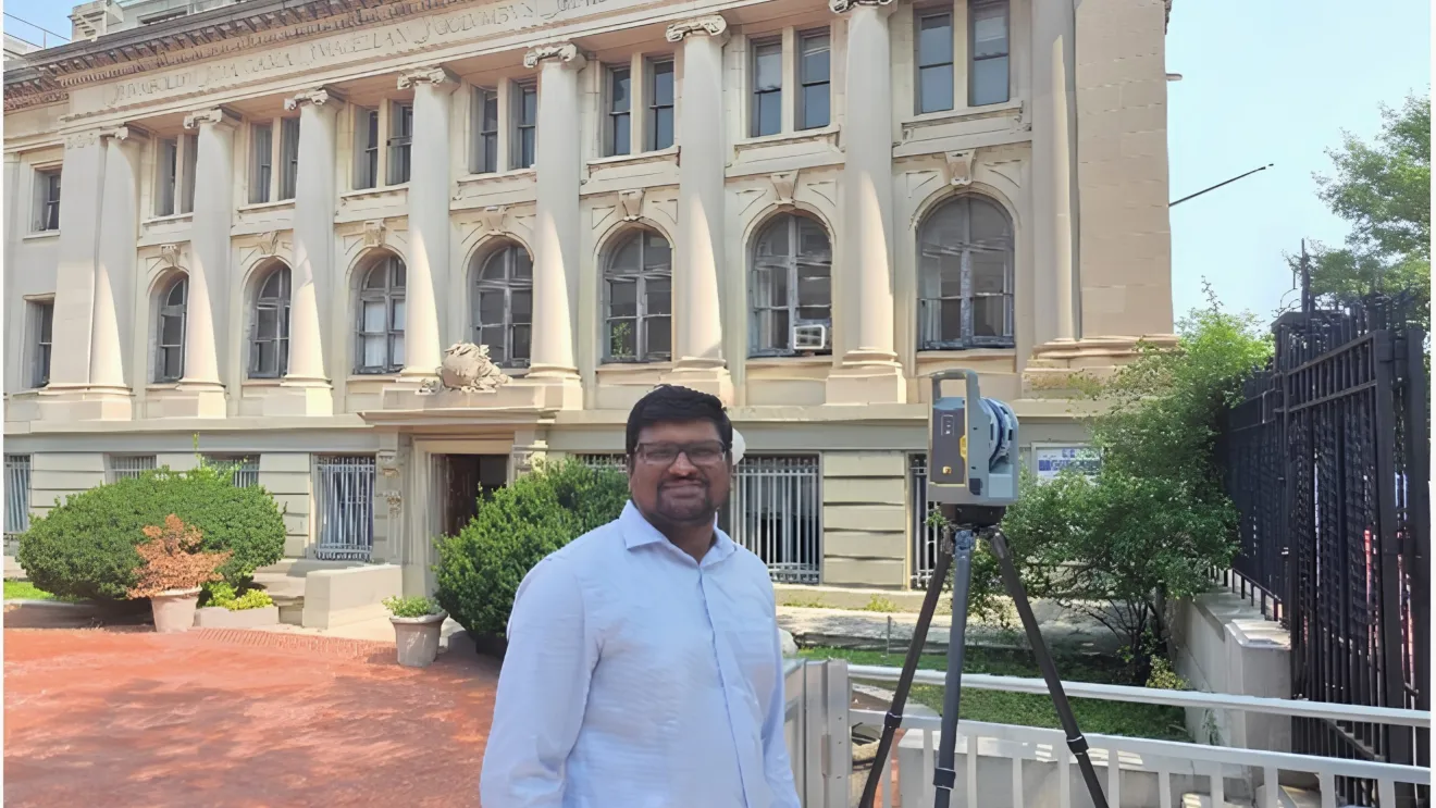 A man stands with a 3-D scanner in front of a beaux arts style building
