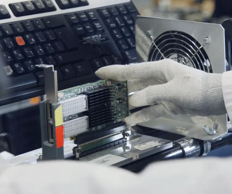A student works testing a circuit board while wearing gloves