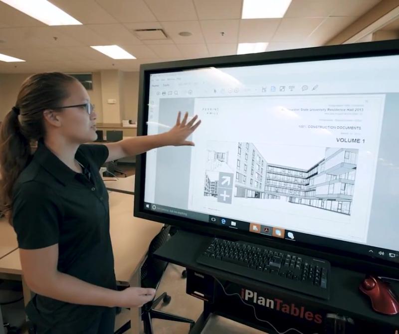 A student demonstrates advanced construction software on a big screen in the classroom
