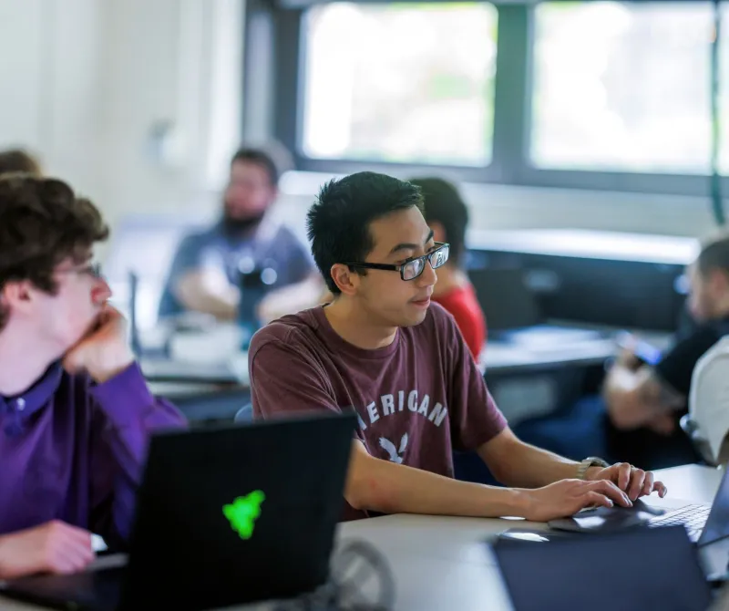 A classroom of students works with hands-on computing projects