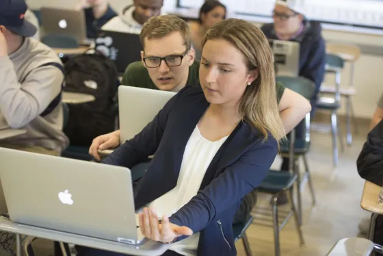Two students discuss their project together in the classroom