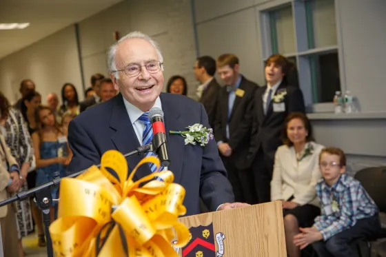a smiling man speaking at a podium