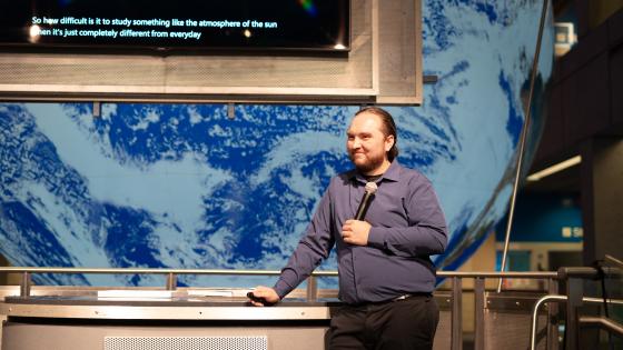 man stands in front of a large projection of planet earth