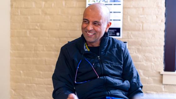 a man smiles while seated in a classroom