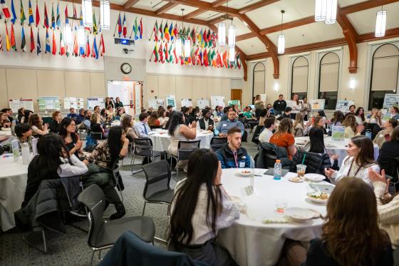 people gathered in a large room with multicolored flags adorning the walls