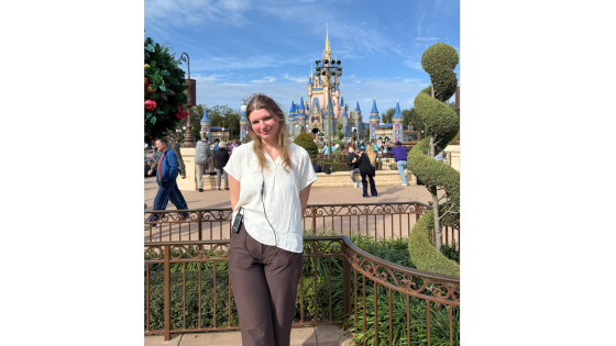 a woman standing in front of a castle at a theme park