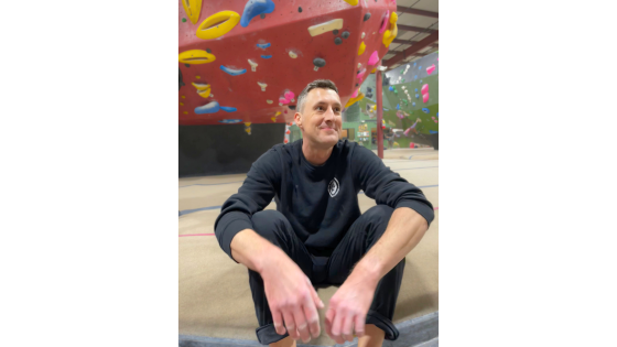 a man sitting on the floor of a rock climbing gym