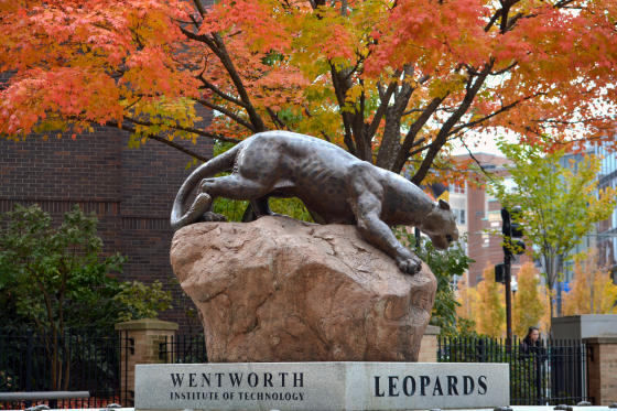 a statue of a leopard surrounded by autumn leaves