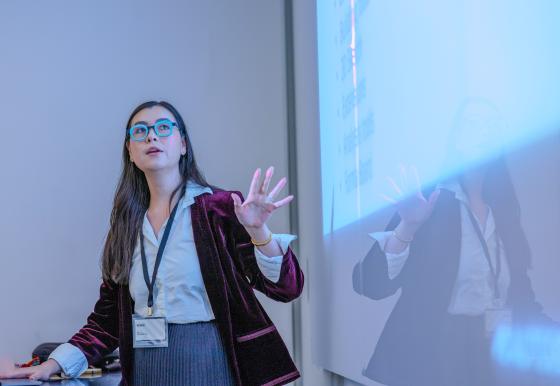 a woman speaking in front of a projection