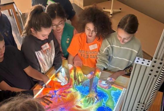 a group of girl scouts interact with an augmented reality teaching device