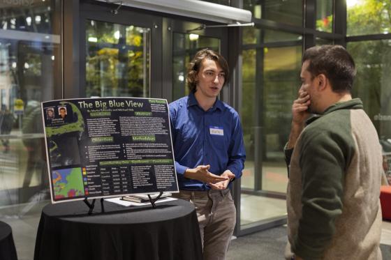 a student shows off an ai-related project to attendees of an event