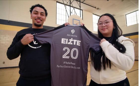 two people hold up an athletic shirt that reads "elite"