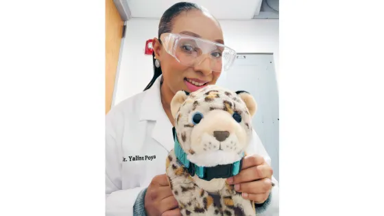 a woman in a lab coat holds a leopard stuffed animal