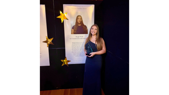 a woman in a black dress holds up an award