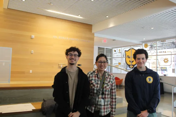 three people pose for the camera in an atrium area