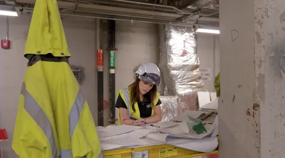 a woman in a hardhat looks over construction plans